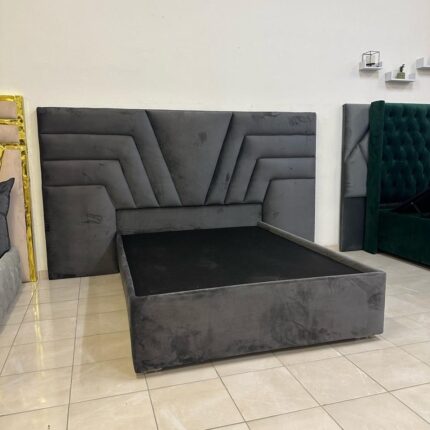 Upholstered grey headboard with a sturdy bed base, neatly made with white bedding.
