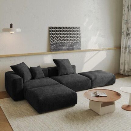 A modern Bria L-shaped couch upholstered in soft black corduroy fabric, featuring deep seating, plush cushions, and a cozy contemporary design ideal for any living room.