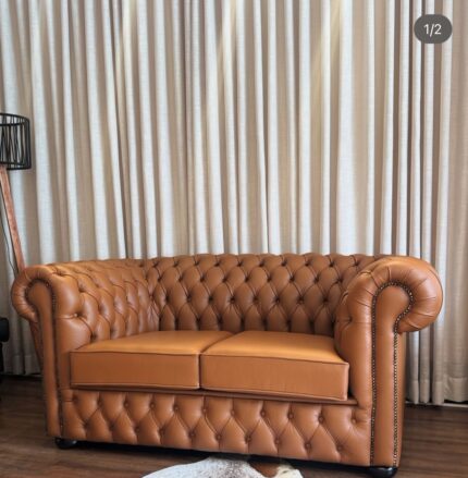 “2-seater Chesterfield sofa in tan brown leather with deep button tufting, rolled arms, and classic design.”