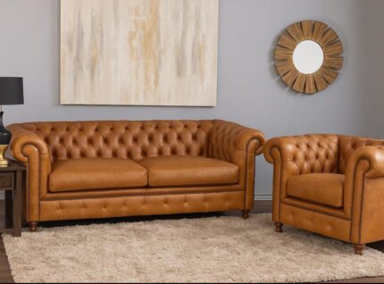 “2- and 1-seater Chesterfield sofas in tan brown leather with deep button tufting and rolled arms, showcasing classic design and rich texture.”