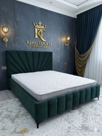 A luxury emerald green velvet Sunburst Headboard Bed by King Touch Furniture, featuring a fan-shaped tufted headboard and a matching vertical channel footboard, styled against a dark stone-textured feature wall with gold accents.
