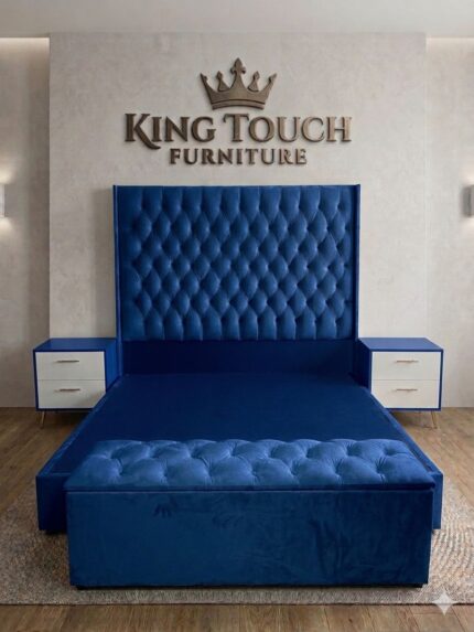 A luxurious royal blue velvet Diamond Tufted Wingback Bed by King Touch Furniture, featuring a high-profile headboard, matching tufted storage ottoman, and two-tone blue and white pedestals with gold hardware.